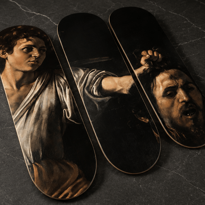 Three skateboard deck tops displayed diagonally on a dark gray marble surface, featuring classical art prints in sepia tones.